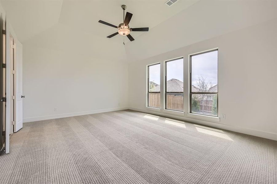 Spare room with light colored carpet, lofted ceiling, ceiling fan, and baseboards