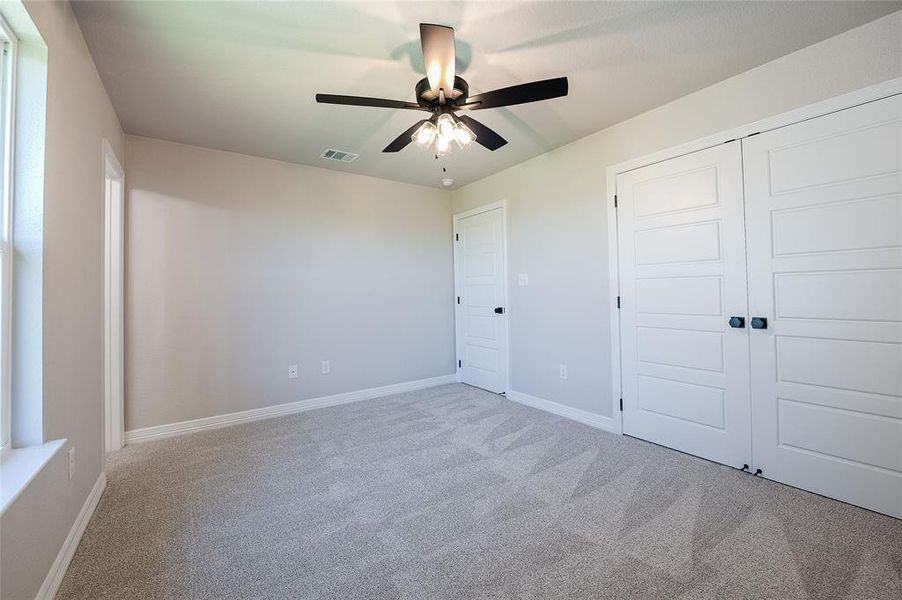 Unfurnished bedroom featuring light colored carpet, a ceiling fan, and a closet
