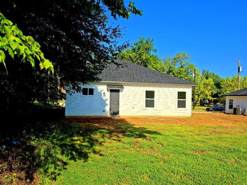 Back of property featuring a lawn and a shingled roof Back of property featuring a lawn and a shingled roof