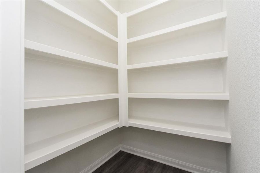 A corner of an empty room with built-in white shelving against a gray floor.