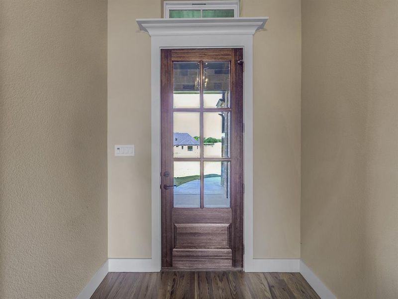 Doorway featuring healthy amount of natural light, wood finished floors, and a textured wall Doorway featuring healthy amount of natural light, wood finished floors, and a textured wall