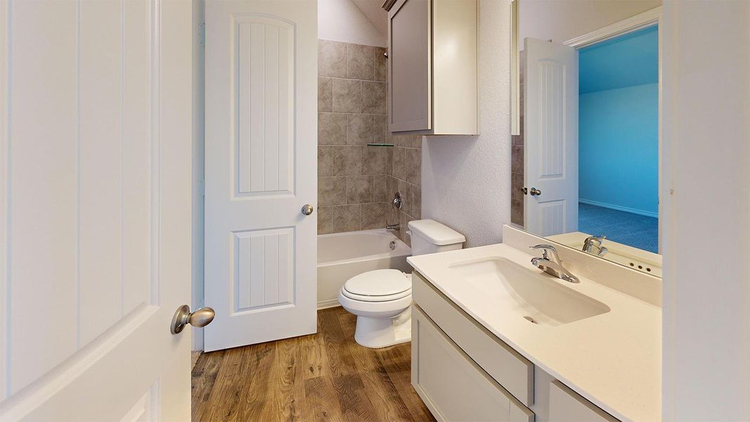 Full bath featuring vanity, dark wood finished floors, and bathing tub / shower combination Full bath featuring vanity, dark wood finished floors, and bathing tub / shower combination
