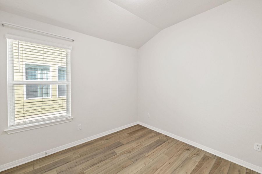 Empty room featuring lofted ceiling and light wood-type flooring Empty room featuring lofted ceiling and light wood-type flooring
