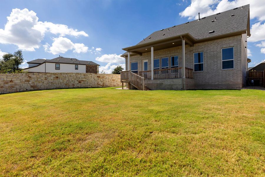 Back of property featuring a fenced backyard, brick siding, and roof with shingles