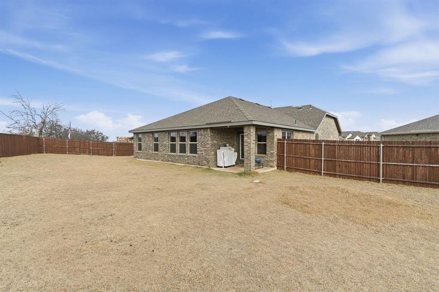 Back of property featuring a patio, brick siding, a fenced backyard, and a shingled roof