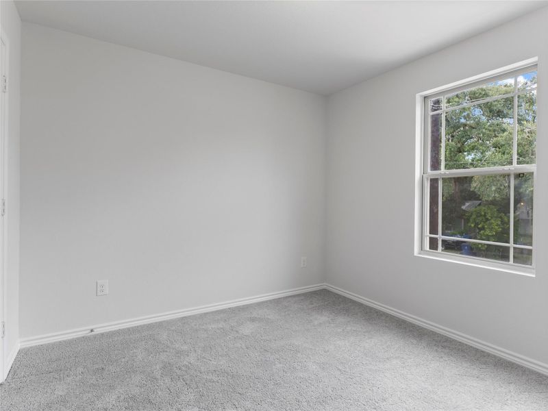 Cozy upstairs bedroom with soft carpeting and a bright window view.