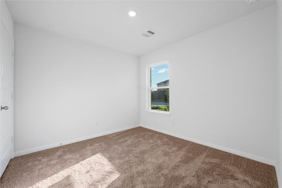 Nestled in the front of this home, the secondary bedroom offers comfort and style with plush carpeting, neutral paint tones, recessed lighting, a large window, and a generously sized closet. Nestled in the front of this home, the secondary bedroom offers comfort and style with plush carpeting, neutral paint tones, recessed lighting, a large window, and a generously sized closet.