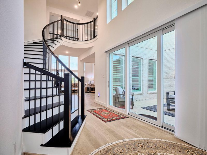 Dramatic curved staircase with custom wood detailing and soaring ceilings.