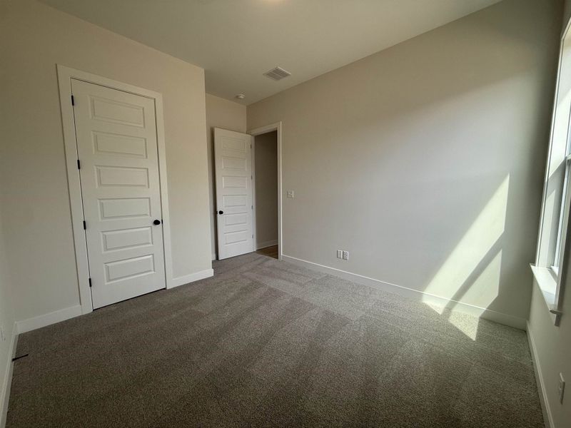 Unfurnished bedroom with dark colored carpet and baseboards