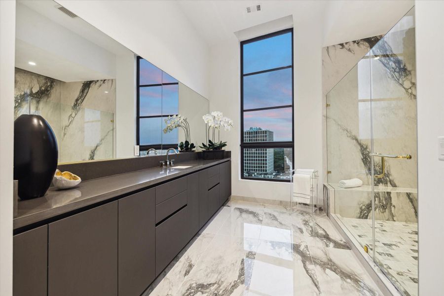 Both Primary Baths feature oversized luxurious showers with stunning slab walls creating striking visual statements. The frameless glass doors, accented with elegant gold details, enhance the modern sophisticated feel, elevating your daily routine into a spa like experience. Both Primary Baths feature oversized luxurious showers with stunning slab walls creating striking visual statements. The frameless glass doors, accented with elegant gold details, enhance the modern sophisticated feel, elevating your daily routine into a spa like experience.