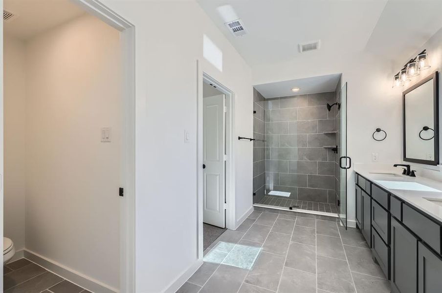 Bathroom featuring toilet, an enclosed shower, vanity, and tile patterned floors