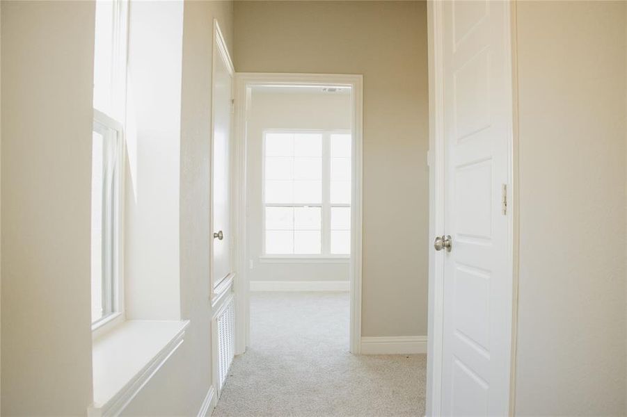 Corridor featuring light colored carpet