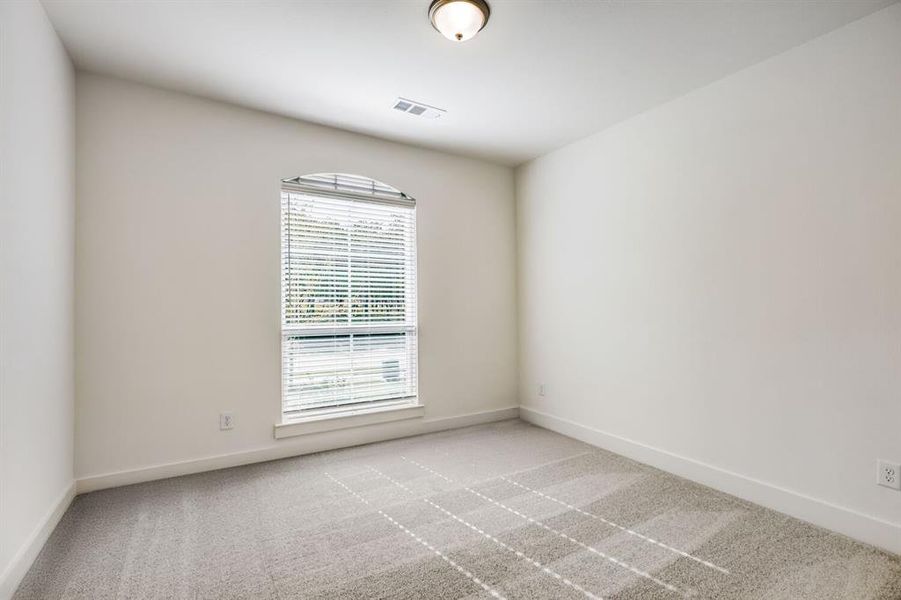 Arched window with blinds, light gray wall-to-wall carpeting, white baseboards, and a flush mount ceiling light fixture