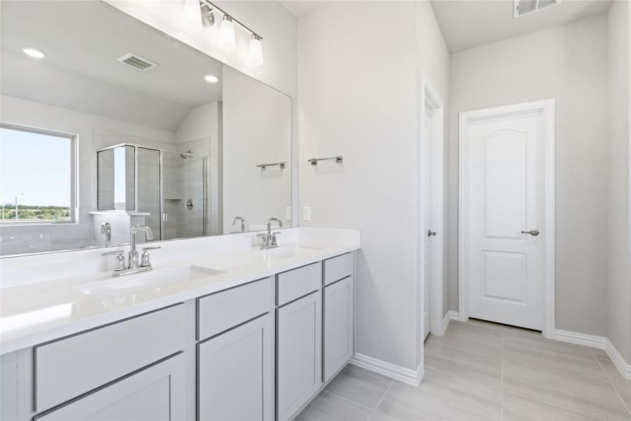 Full bath featuring a shower stall, double vanity, light tile patterned flooring, recessed lighting, and vaulted ceiling