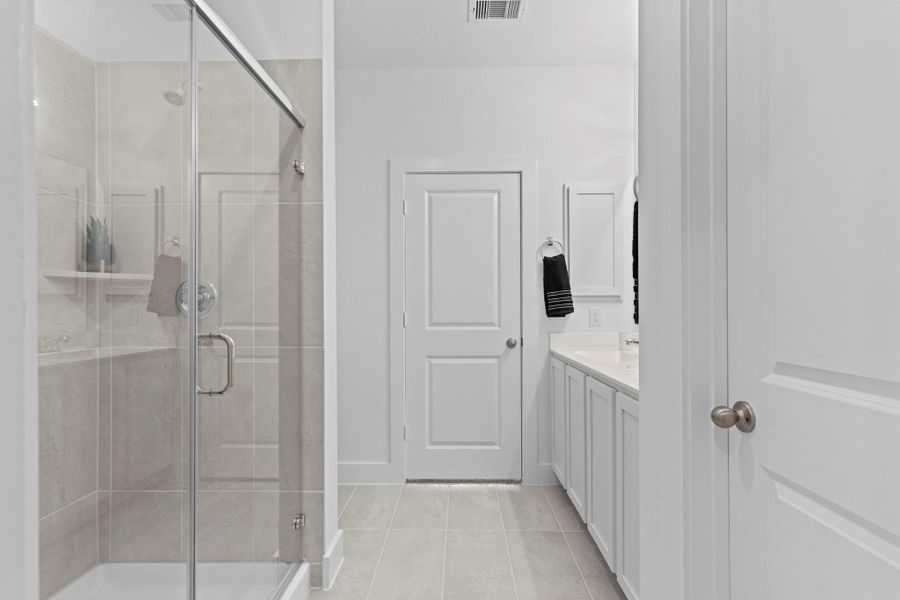 The luxurious primary bathroom showcases a beautifully tiled walk-in shower with a sleek glass enclosure, a cultured marble double-sink vanity, and abundant cabinetry. The central door provides direct access back to the primary bedroom, allowing for a seamless and private layout. **Image Representative of Plan Only and May Vary as Built**. The luxurious primary bathroom showcases a beautifully tiled walk-in shower with a sleek glass enclosure, a cultured marble double-sink vanity, and abundant cabinetry. The central door provides direct access back to the primary bedroom, allowing for a seamless and private layout. **Image Representative of Plan Only and May Vary as Built**.