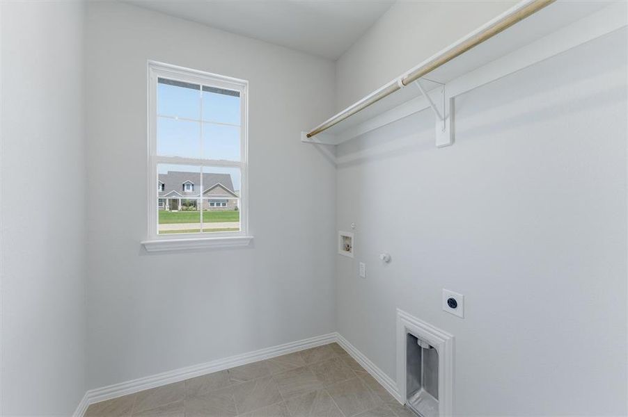 Utility room featuring a window, tile flooring, wall-mounted shelving, and plumbing/electrical hookups Utility room featuring a window, tile flooring, wall-mounted shelving, and plumbing/electrical hookups