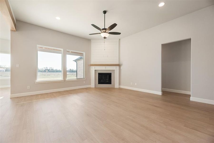 Unfurnished living room featuring light wood-type flooring, a fireplace, recessed lighting, and a ceiling fan Unfurnished living room featuring light wood-type flooring, a fireplace, recessed lighting, and a ceiling fan
