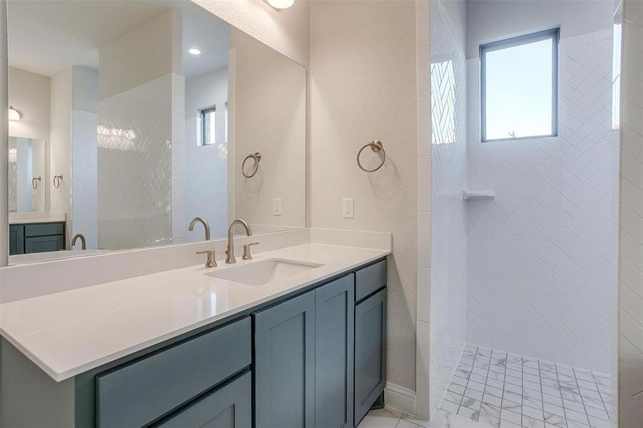 Bathroom with a tile shower, tile patterned flooring, and vanity