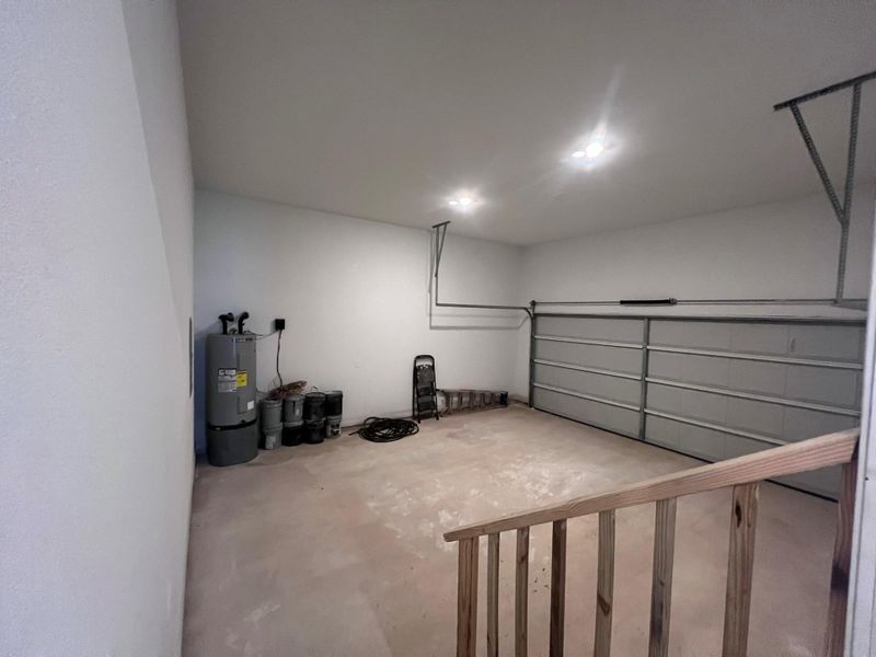 An attached garage features concrete flooring, recessed overhead lighting, and a modern roll-up door. An attached garage features concrete flooring, recessed overhead lighting, and a modern roll-up door.