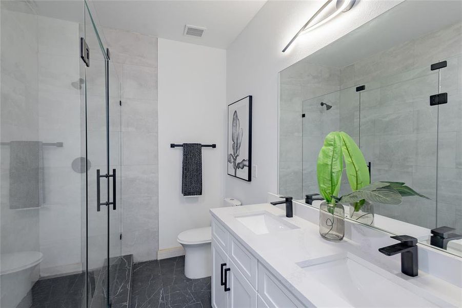 Bathroom featuring double vanity, a shower stall, and dark marble finish flooring Bathroom featuring double vanity, a shower stall, and dark marble finish flooring