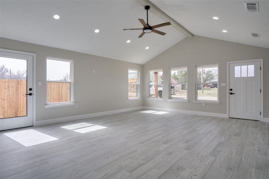 Unfurnished living room featuring beamed ceiling, light wood-style floors, visible vents, and baseboards