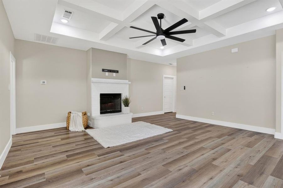 Wood burning fire place with white brick and open concept living room and tray boxed ceilings.  High baseboards and luxury wood looking vinyl flooring.