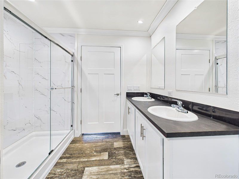 Five-piece ensuite featuring dual vanities with black counters and white cabinetry.