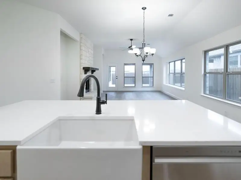 Details with pendant lighting, sink, a brick fireplace, stainless steel dishwasher, and a notable chandelier