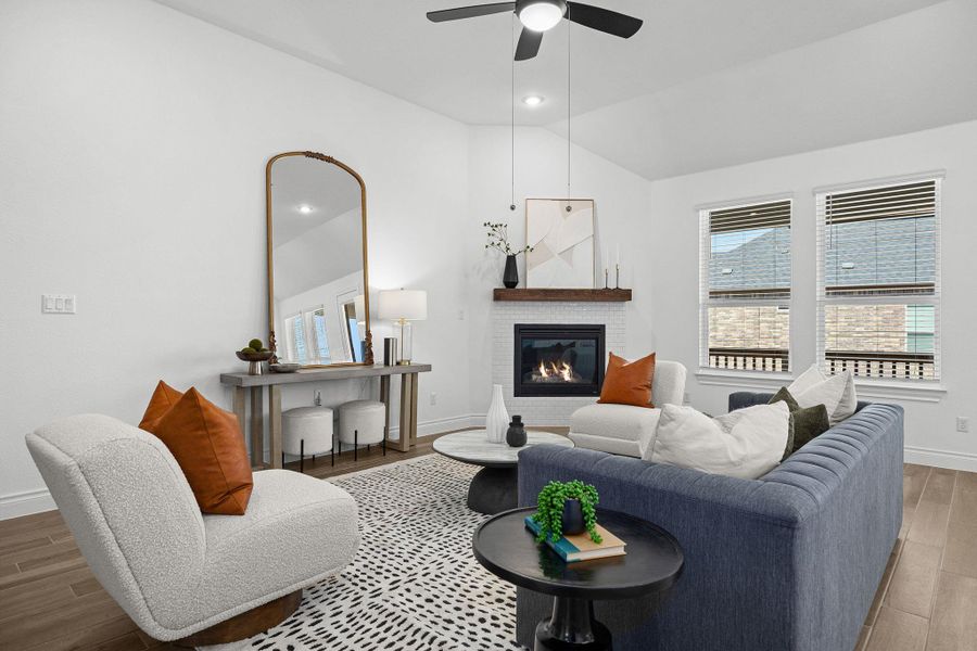 Living area with wood finished floors, vaulted ceiling, a brick fireplace, recessed lighting, and a ceiling fan