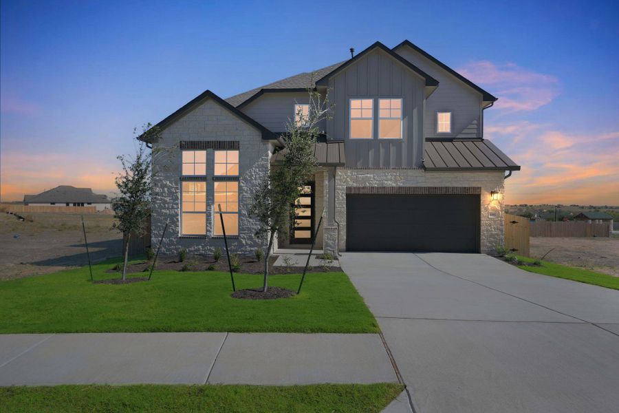 View of front of house with stone siding, a garage, driveway, a standing seam roof, and a metal roof