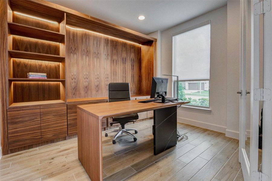 Home office with sleek wood paneling and built-in shelving. It features a large window allowing natural light, a stylish desk, and a comfortable office chair. Ideal for a productive workspace. Home office with sleek wood paneling and built-in shelving. It features a large window allowing natural light, a stylish desk, and a comfortable office chair. Ideal for a productive workspace.