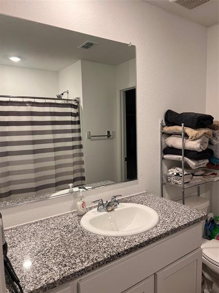 Full bathroom with curtained shower, vanity, a textured wall, and recessed lighting Full bathroom with curtained shower, vanity, a textured wall, and recessed lighting