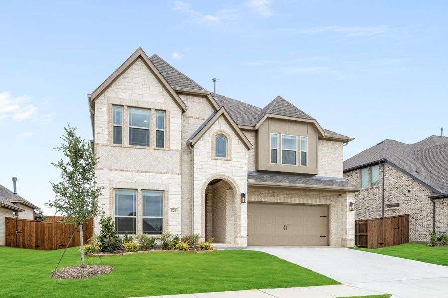 Two-story home with light stone exterior, arched entry, two-car garage, and green front lawn Two-story home with light stone exterior, arched entry, two-car garage, and green front lawn