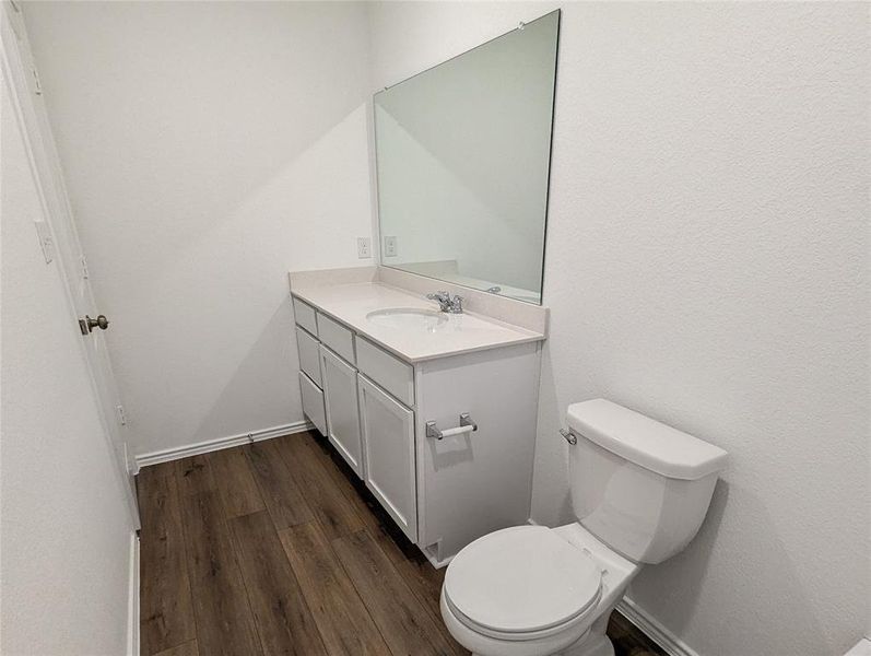 A well-appointed half-bath offers convenience and style with its sleek vanity and rich hardwood flooring.