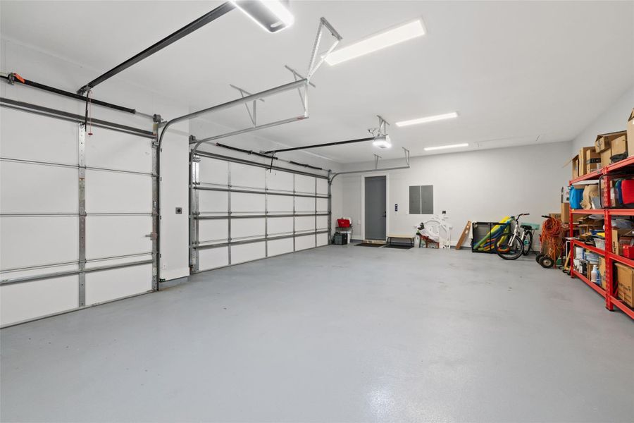 Spacious garage featuring two overhead doors, a neutral-toned epoxy floor, and recessed lighting