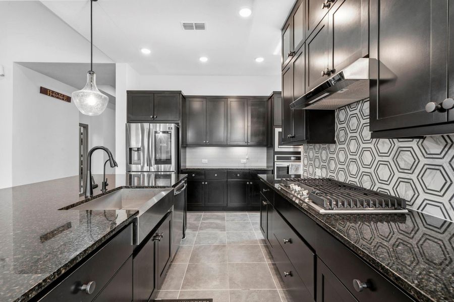 Chef’s kitchen featuring gas cooktop, designer backsplash, and sleek stainless steel appliances.
