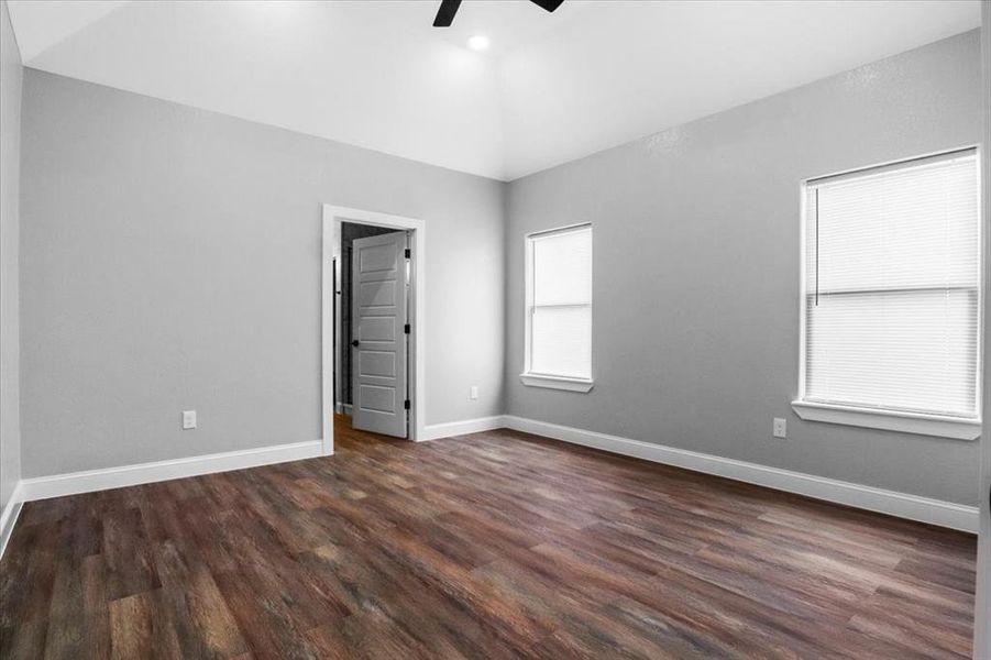 Empty room featuring ceiling fan, dark wood-type flooring, and vaulted ceiling