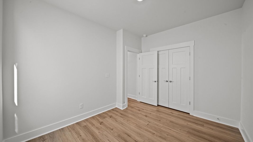 Thoughtfully designed secondary bedrooms featuring hardwood flooring and tasteful detail