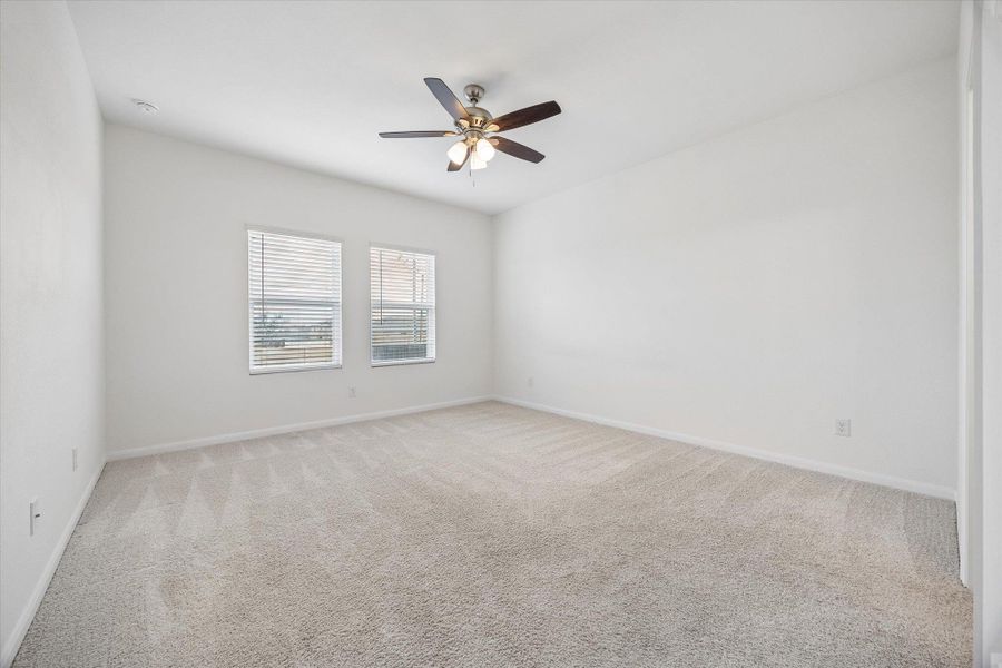Empty room with light carpet and a ceiling fan