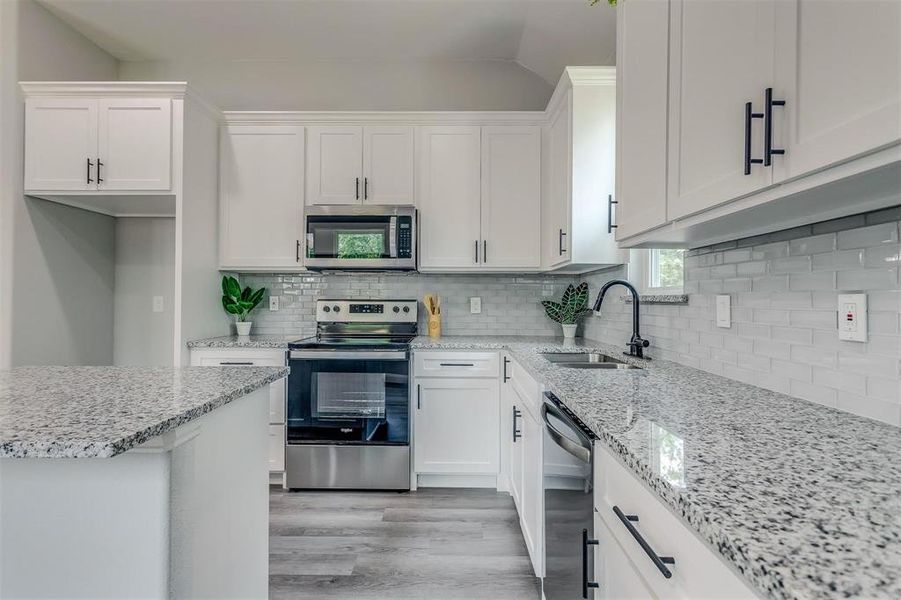 Kitchen with white cabinetry, sink, and stainless steel appliances