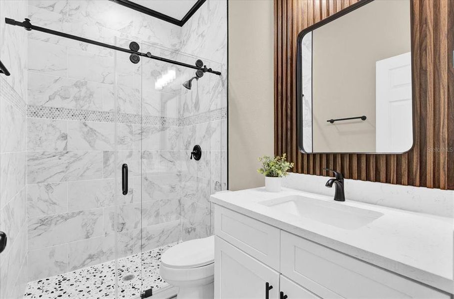 Beautiful guest bathroom with slated panel, white cabinets and quartz countertops