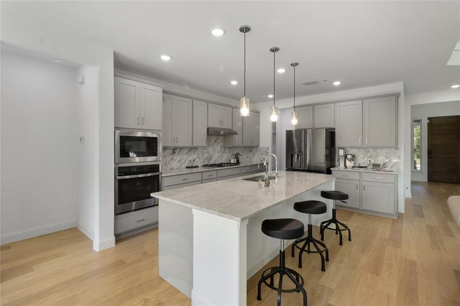 Kitchen featuring light wood-finish flooring, recessed lighting, and an island with pendant lights