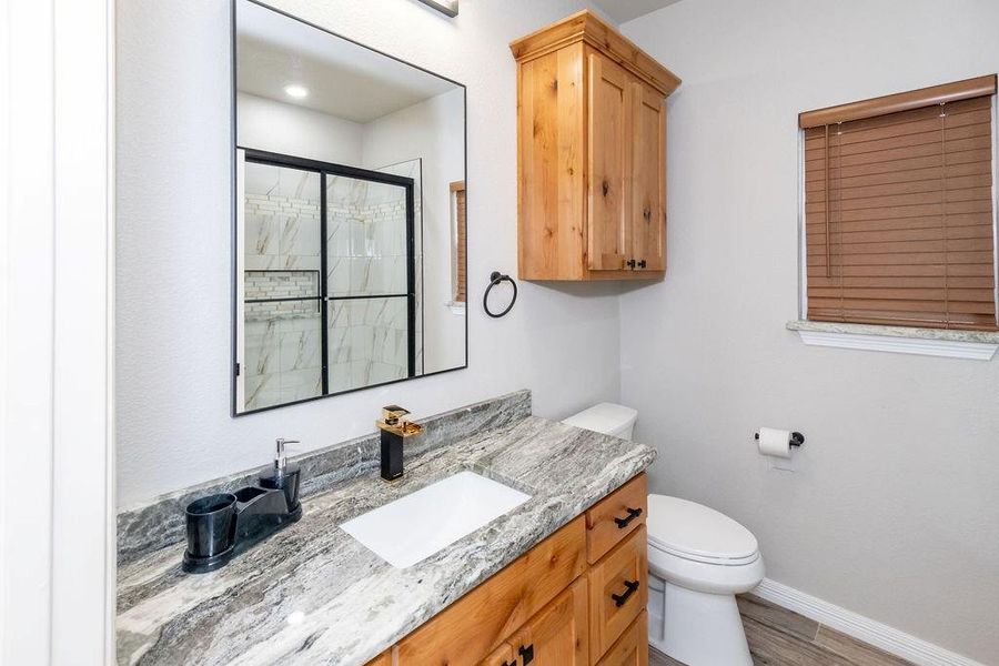 Bathroom featuring vanity, hardwood / wood-style flooring, a shower with door, and toilet