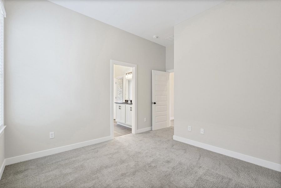 Spacious room featuring vaulted ceilings, light gray carpet, and white baseboards Spacious room featuring vaulted ceilings, light gray carpet, and white baseboards