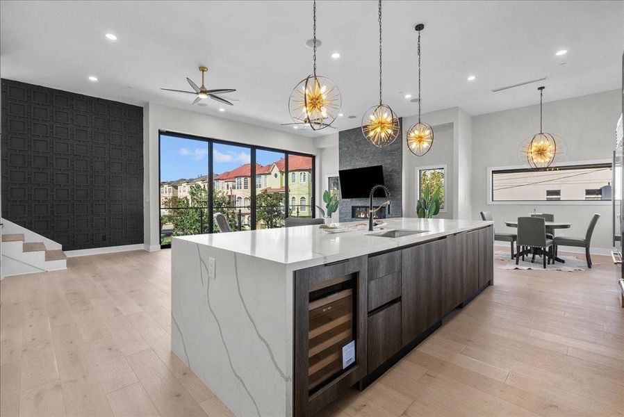 This modern open-concept kitchen and living space features sleek cabinetry, a large marble island, and striking pendant lights. Expansive windows offer abundant natural light and views, while a stylish fireplace adds warmth. Elegant dining and seating areas make it perfect for entertaining. This modern open-concept kitchen and living space features sleek cabinetry, a large marble island, and striking pendant lights. Expansive windows offer abundant natural light and views, while a stylish fireplace adds warmth. Elegant dining and seating areas make it perfect for entertaining.