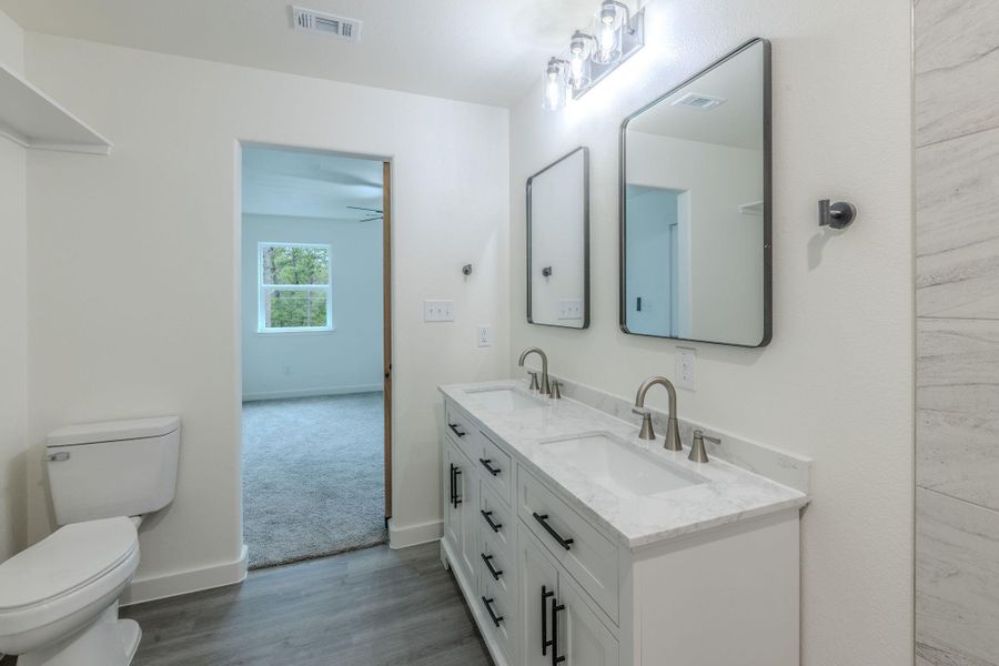 Dual vanity with sleek fixtures and a spacious shower elevate this bathroom's modern appeal. Dual vanity with sleek fixtures and a spacious shower elevate this bathroom's modern appeal.