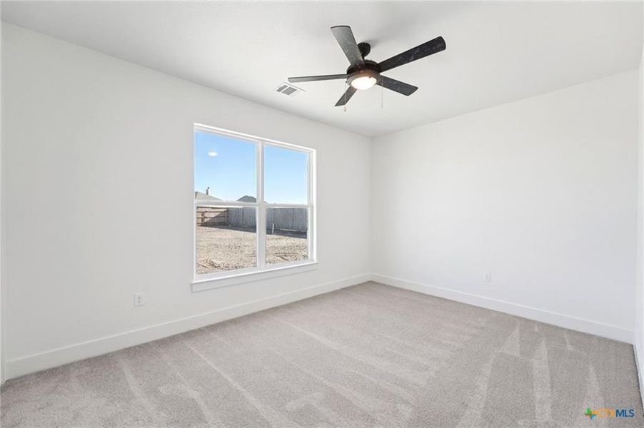 A well-lit bedroom provides comfort with soft carpeting and a clear backyard view. A well-lit bedroom provides comfort with soft carpeting and a clear backyard view.