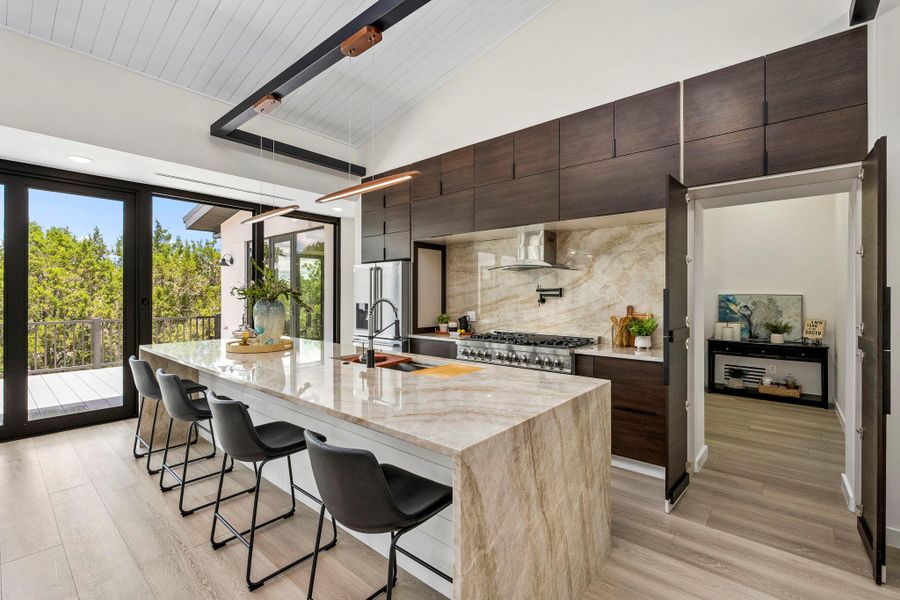 Kitchen with a kitchen breakfast bar, dark wood finish cabinets, light stone countertops, and a vaulted wooden ceiling
