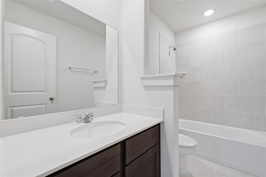 Modern bathroom featuring a single vanity with a white countertop, undermount sink, and dark wood-finish cabinetry
