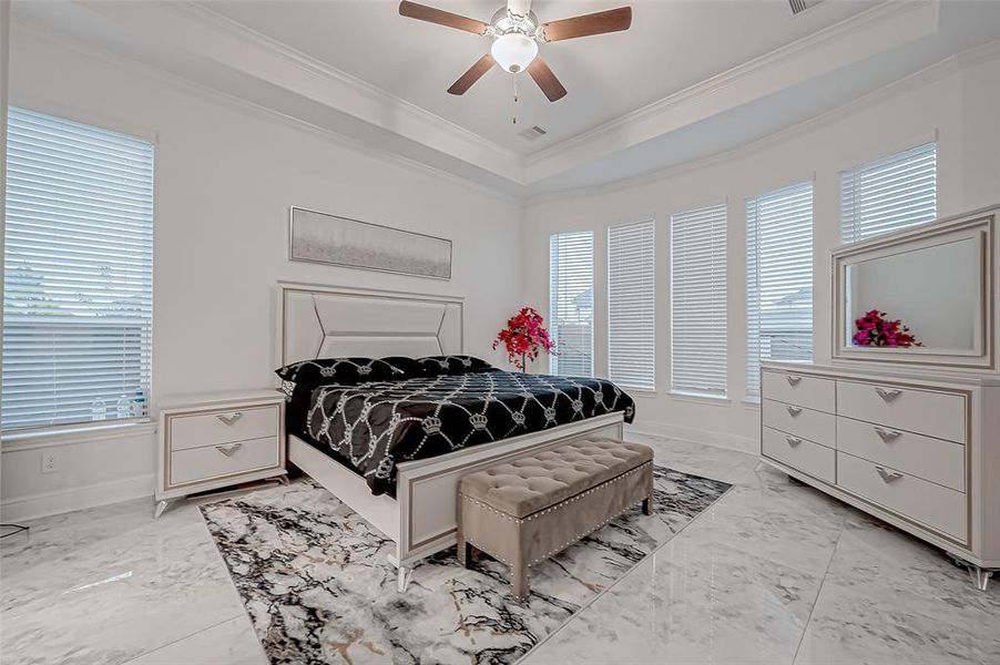 Two Lavish Primary Suites on the Main Level. Pictured is the First Primary Suite: Curved wall of windows for abundant natural light, tile marbled flooring and Tray ceiling.